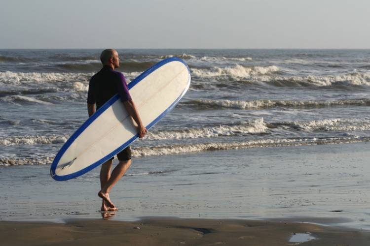 A man with a surfboard on a Port Aransas beach