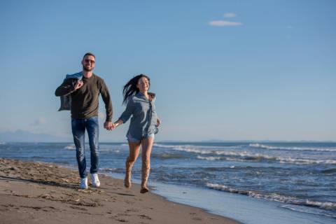 Fall in Texas A couple running on a Port Aransas beach on a fall vacation in Texas.